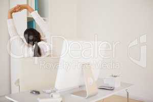 Casual businesswoman stretching at her desk