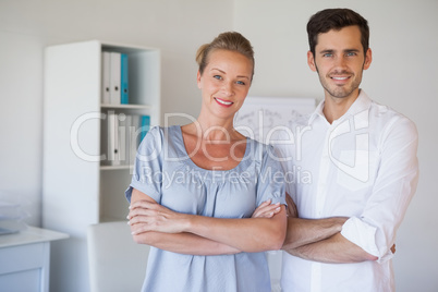 Casual business team smiling at camera with arms crossed