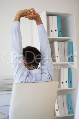 Casual businessman stretching in swivel chair