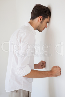 Casual stresed businessman leaning against the wall