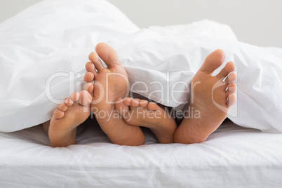 Couples feet sticking out from under duvet