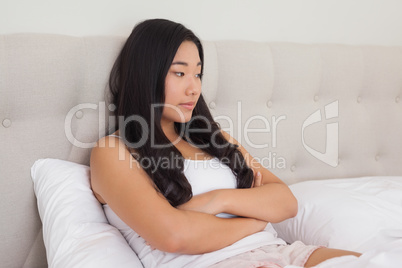 Woman sitting in bed with arms crossed