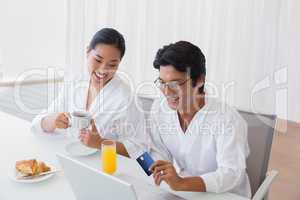 Couple in bathrobes shopping online in the morning