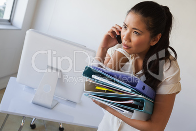 Casual businesswoman balancing coffee on pile of folders