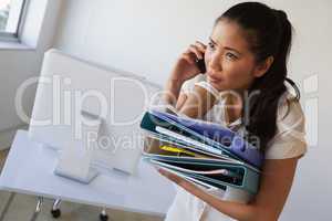 Casual businesswoman balancing coffee on pile of folders