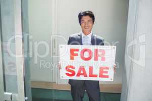 Confident estate agent standing at front door showing for sale s