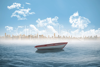 Small boat in the sea with city on horizon