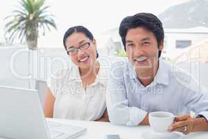 Smiling couple having breakfast together using laptop