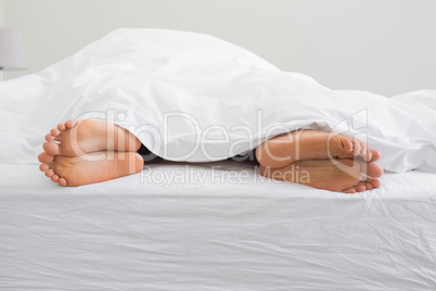 Couples feet sticking out from under duvet