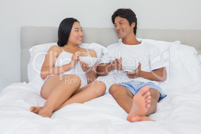 Happy couple having breakfast in bed