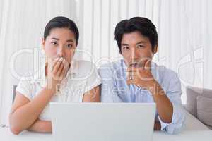 Worried couple using laptop together