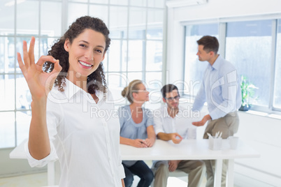 Casual happy businesswoman making ok sign to camera