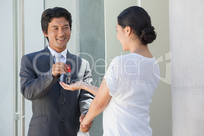 Smiling estate agent giving the key to buyer