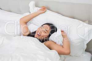 Smiling woman lying in bed in the morning