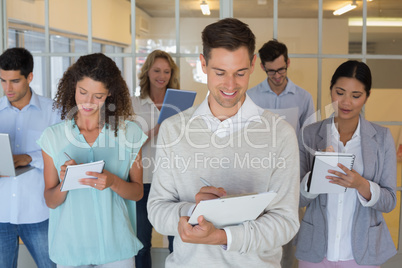 Casual boss standing in front of his team all taking notes