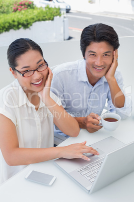 Smiling couple having breakfast together using laptop