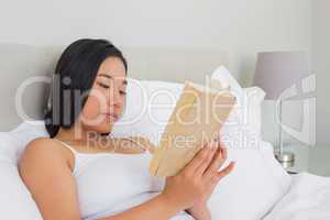 Smiling woman lying on bed reading