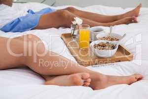 Couple lying on bed with breakfast on a tray