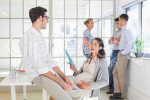 Pregnant businesswoman laughing with colleague