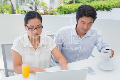 Smiling couple having breakfast together using laptop