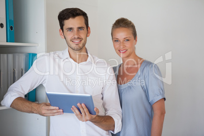 Casual business team smiling at camera man holding tablet