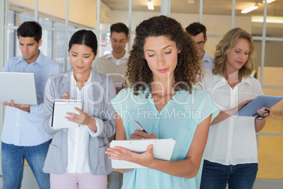 Casual boss standing in front of her team all taking notes