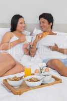 Happy couple having breakfast in bed