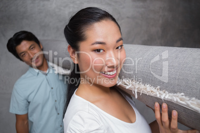 Happy couple holding a rolled up rug