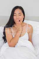 Smiling woman lying in bed yawning in the morning