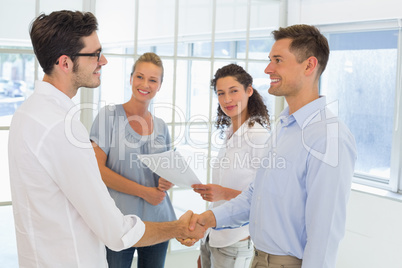 Casual businessmen shaking hands and smiling