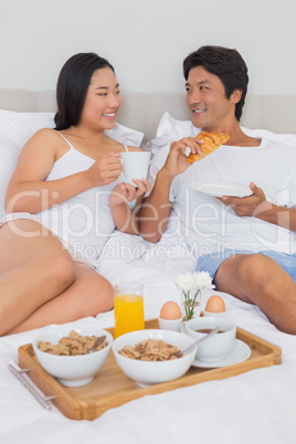 Happy couple having breakfast in bed