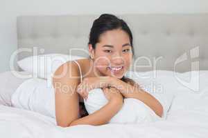 Smiling asian woman lying on bed