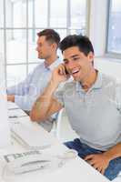 Casual businessman laughing on the phone at his desk