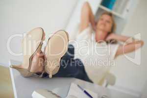 Casual businesswoman sitting at her desk with feet up