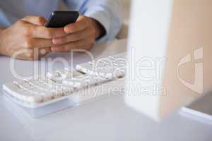 Businessman texting on phone at desk