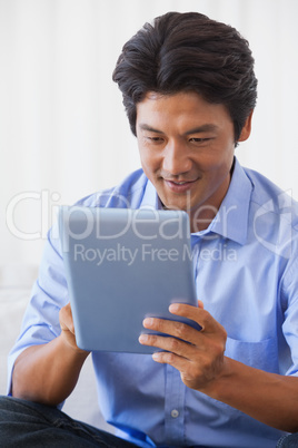 Happy man sitting on couch using tablet