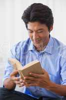 Happy man sitting on couch reading