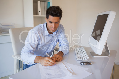 Casual businessman sitting at desk writing