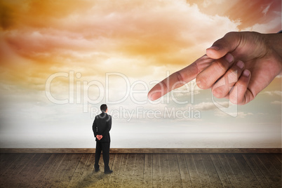 Giant hand pointing at businessman standing and looking