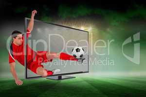 Fit football player kicking ball through tv