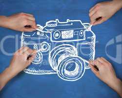 Composite image of multiple hands drawing camera with chalk