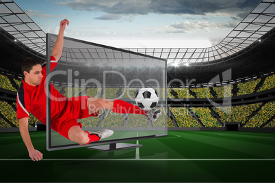 Fit football player kicking ball through tv