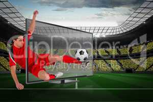 Fit football player kicking ball through tv