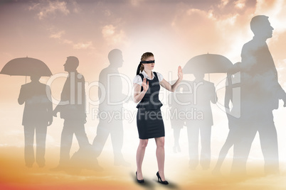 Composite image of redhead businesswoman in a blindfold