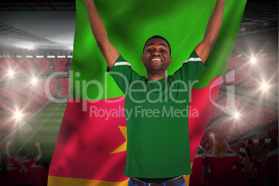 Cheering football fan in green jersey holding cameroon flag