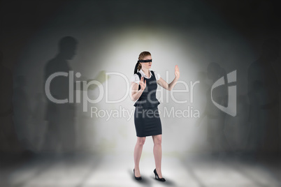 Composite image of redhead businesswoman in a blindfold