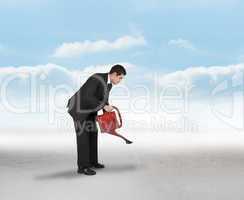 Composite image of businessman watering with red can