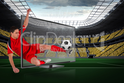 Fit football player kicking ball through tv