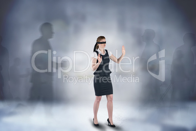 Composite image of redhead businesswoman in a blindfold