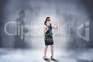 Composite image of redhead businesswoman in a blindfold